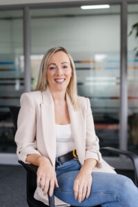 Headshot of Nexus Chief People Office, Hayley Berry, sitting on a chair on a blurred office background